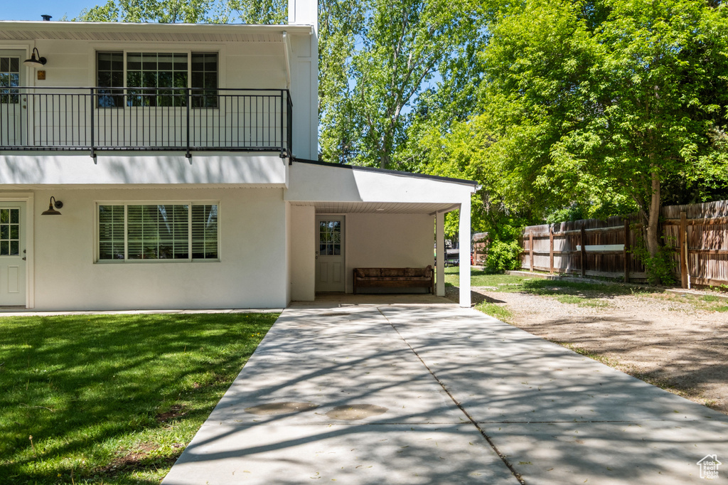 View of front of home featuring a balcony, a carport, concrete driveway, and stucco siding