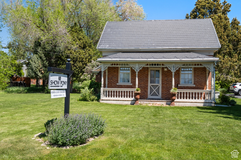 View of front facade with covered porch, a front yard, and brick siding