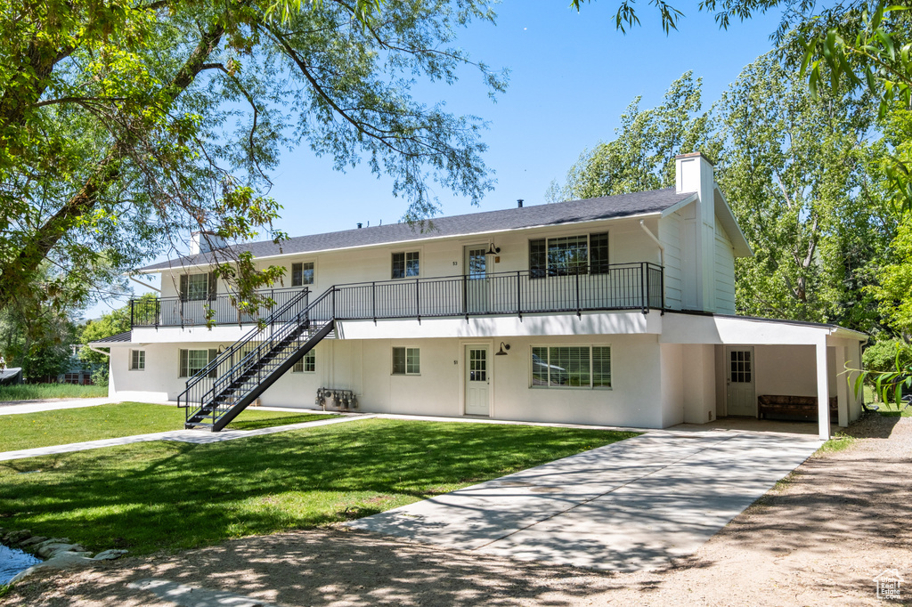 View of property with concrete driveway, stairs, and a carport