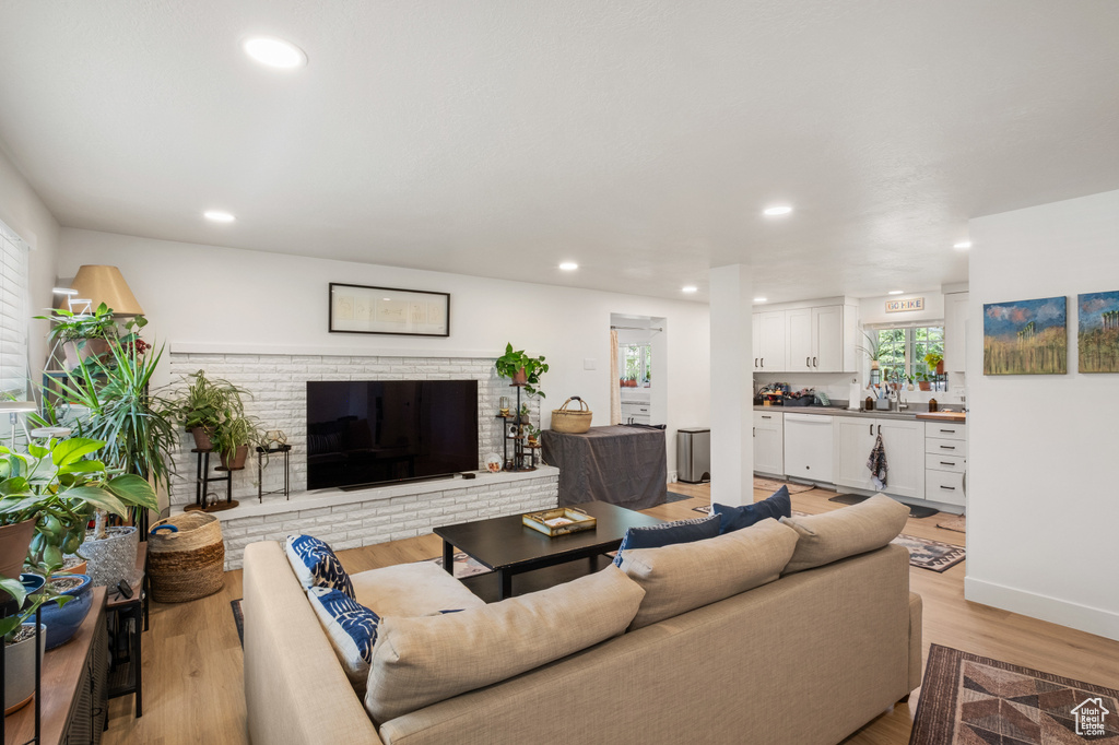 Living room with light wood-style flooring, recessed lighting, and a brick fireplace