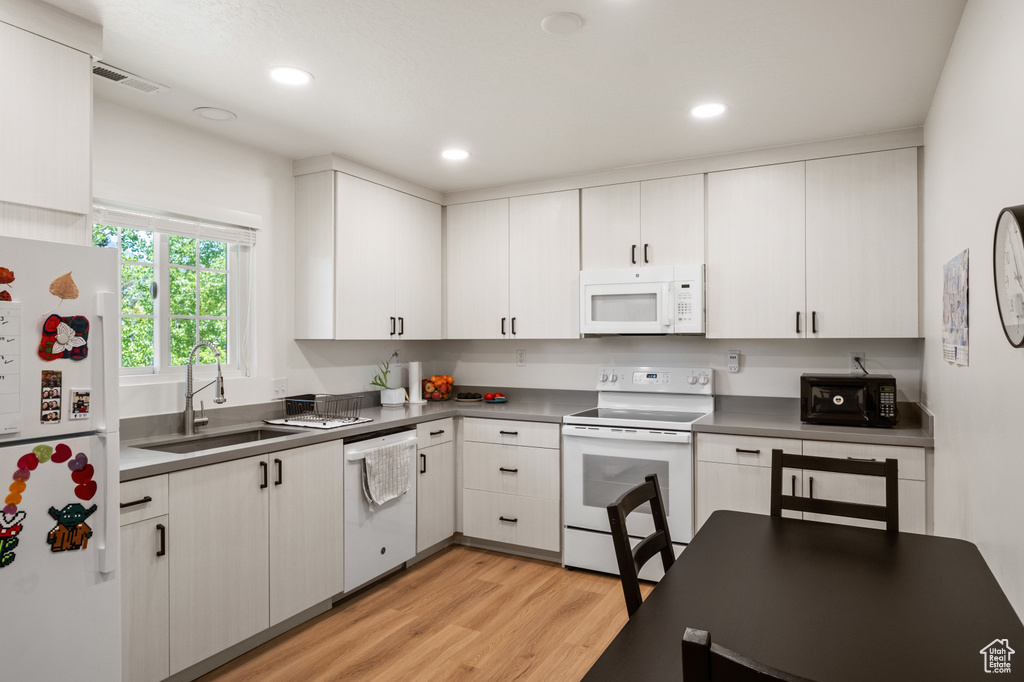 Kitchen featuring white appliances, light wood-style flooring, white cabinetry, and recessed lighting
