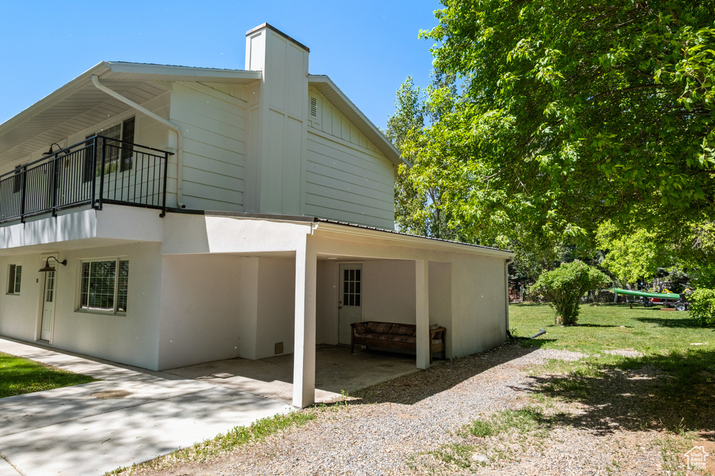View of side of home featuring driveway, a balcony, and a carport
