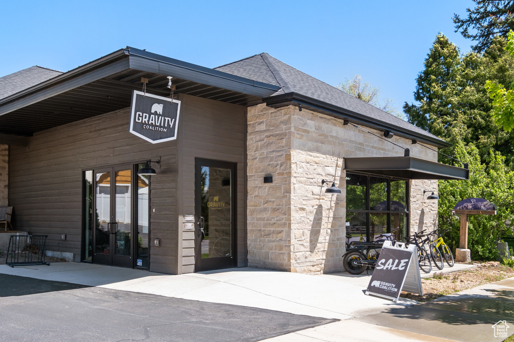 Entrance to property with stone siding, a shingled roof, and french doors