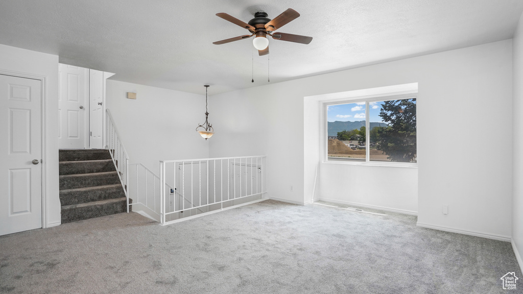 Carpeted empty room with ceiling fan and baseboards