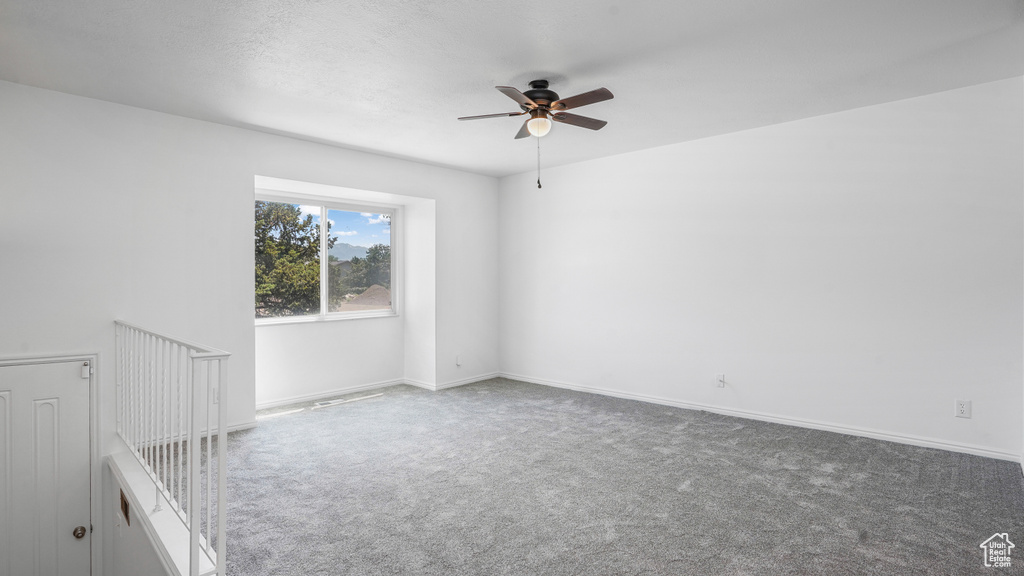 Carpeted spare room with a ceiling fan and baseboards