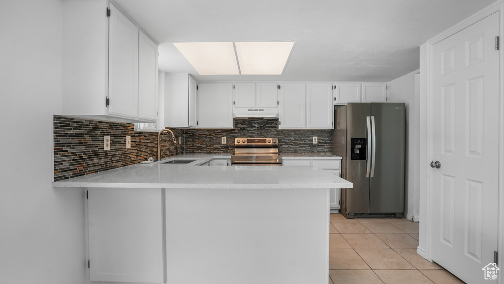 Kitchen featuring stainless steel appliances, under cabinet range hood, tasteful backsplash, white cabinetry, and a peninsula