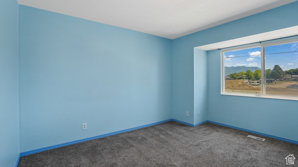 Carpeted spare room featuring baseboards