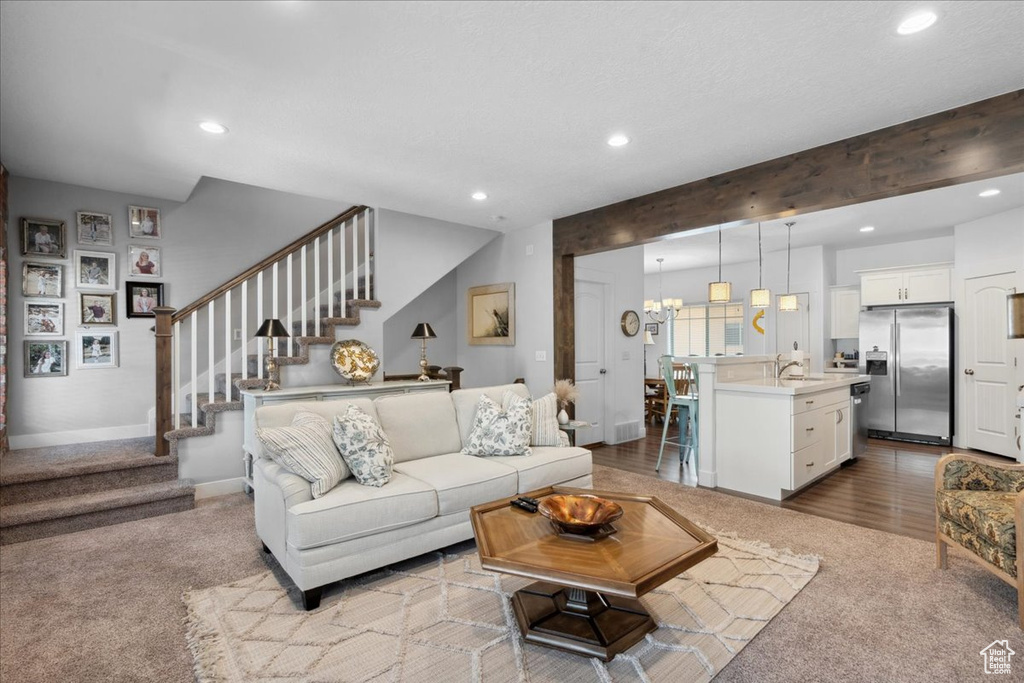 Living area with carpet flooring, recessed lighting, and stairs