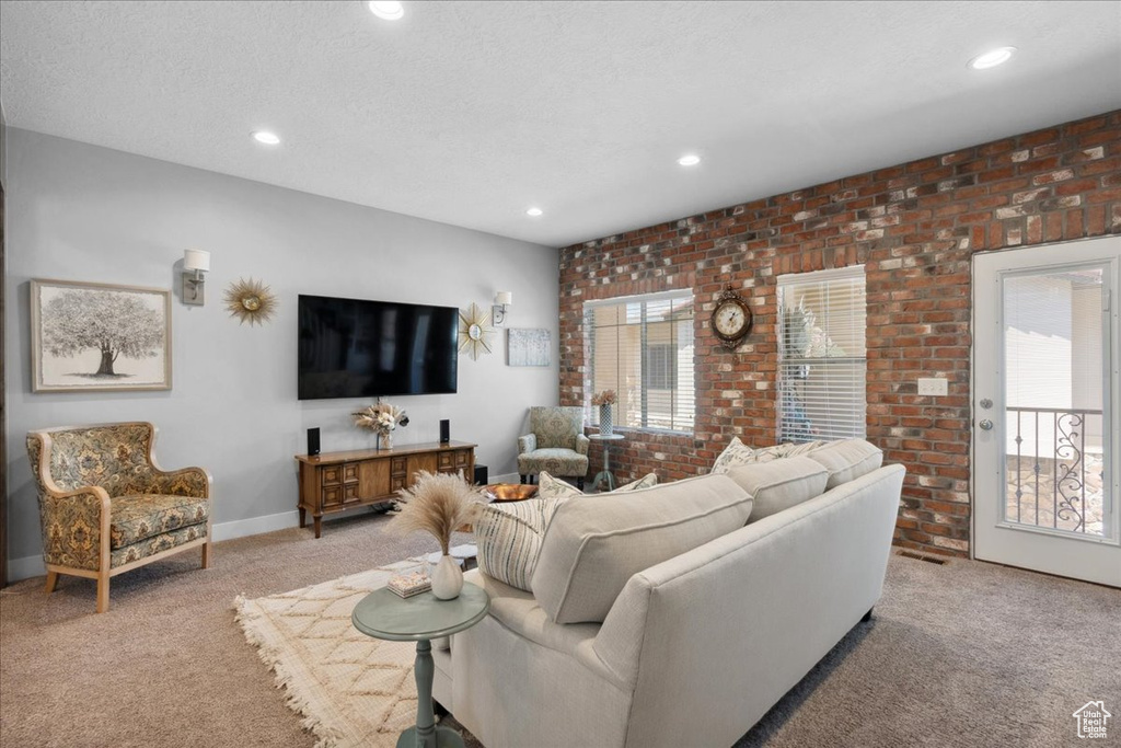 Living area featuring carpet flooring, recessed lighting, and brick wall