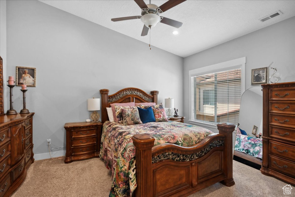 Bedroom featuring light carpet, ceiling fan, and vaulted ceiling