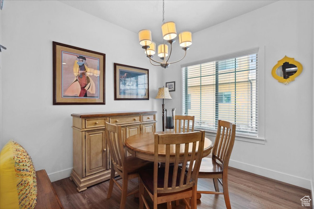 Dining area with a chandelier and dark wood-type flooring