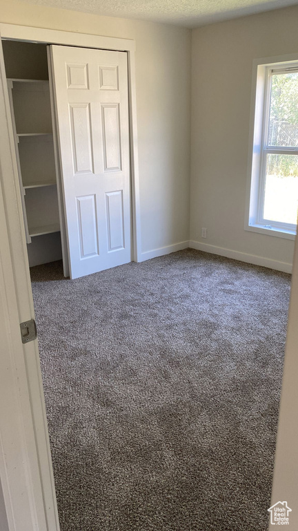 Unfurnished bedroom with carpet floors, a closet, and a textured ceiling