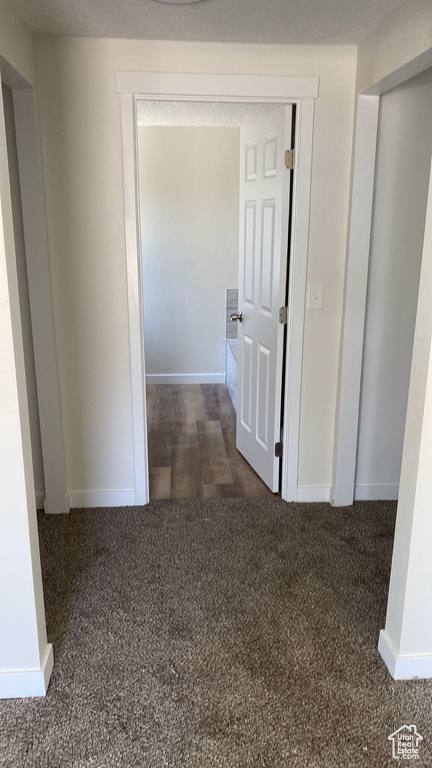 Hallway featuring dark carpet