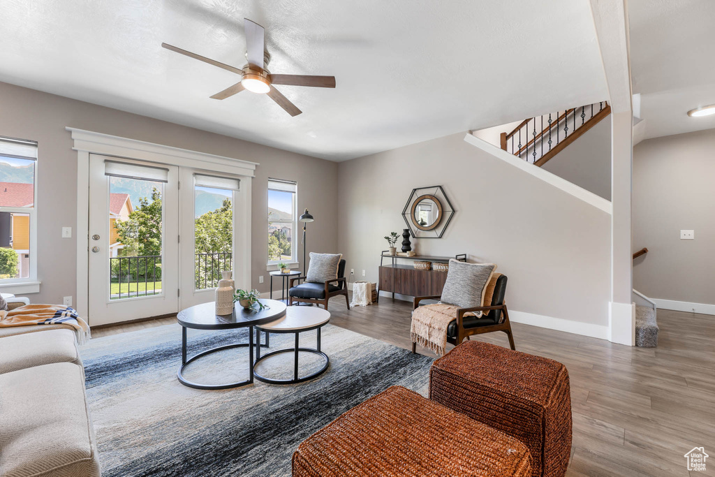 Living area with plenty of natural light, wood finished floors, and a ceiling fan