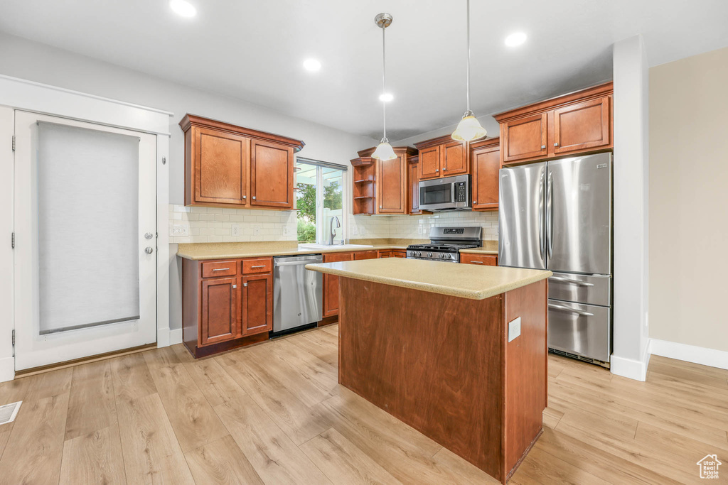 Kitchen with appliances with stainless steel finishes, light wood-style flooring, light countertops, tasteful backsplash, and recessed lighting