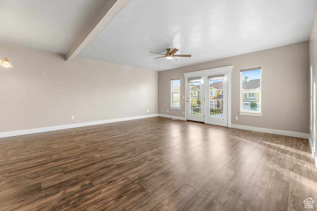 Empty room featuring ceiling fan, dark wood-type flooring, and beam ceiling