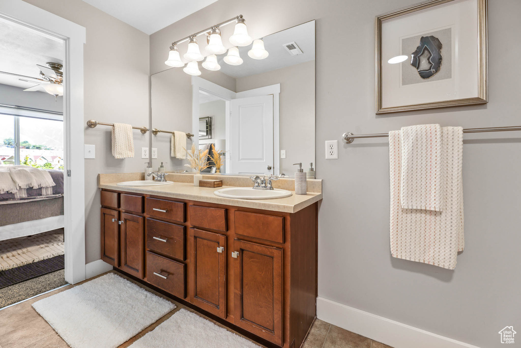 Ensuite bathroom featuring double vanity, tile patterned floors, and a ceiling fan