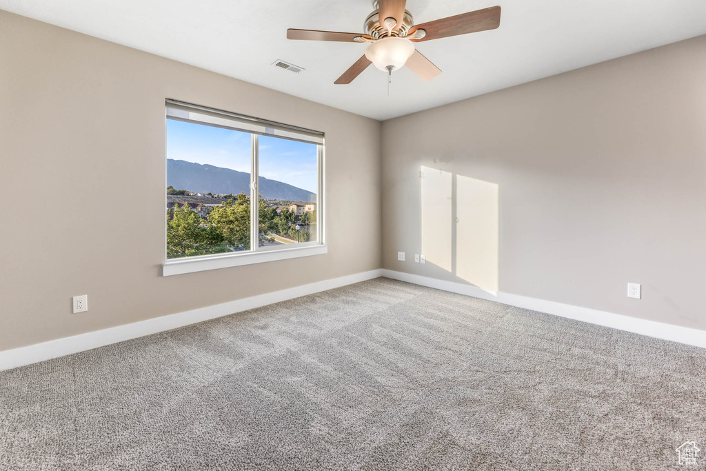 Empty room with carpet, ceiling fan, and a mountain view