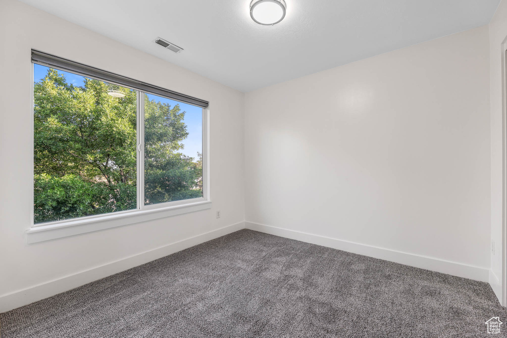 Empty room with plenty of natural light and dark colored carpet