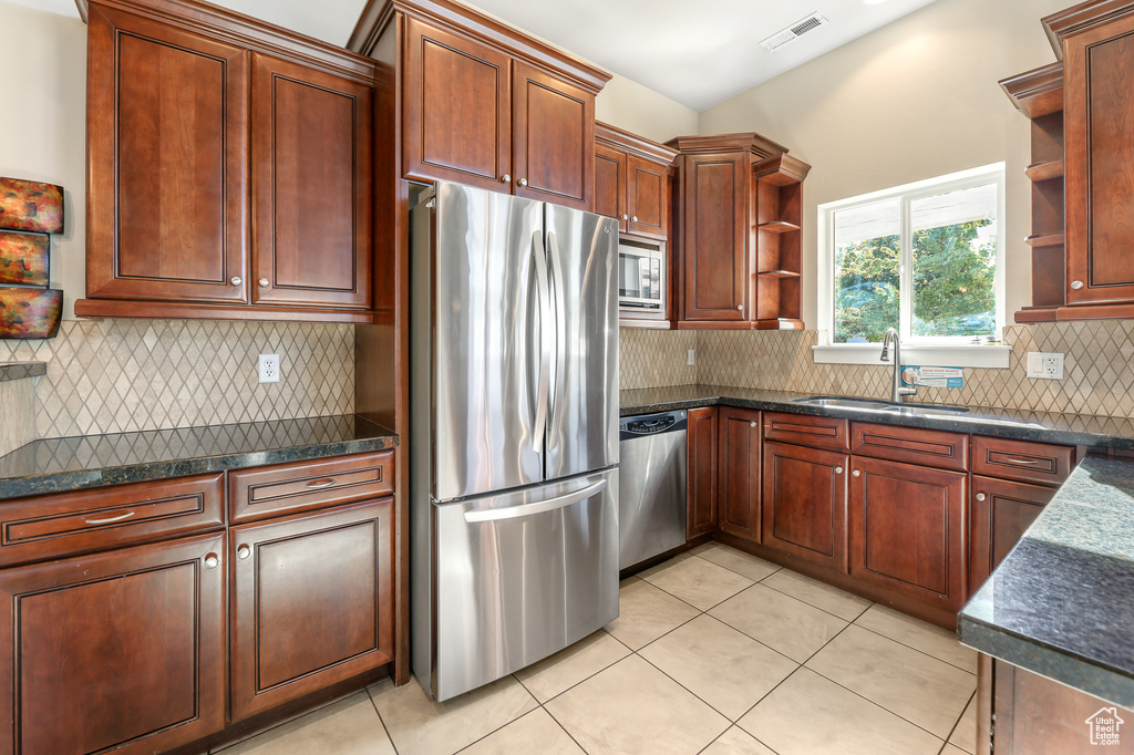 Kitchen featuring stainless steel appliances, open shelves, light tile patterned floors, and backsplash