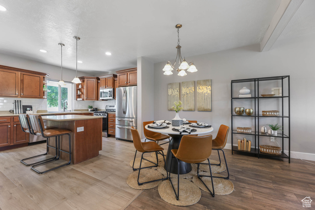 Kitchen featuring stainless steel appliances, wood finished floors, a kitchen island, brown cabinets, and recessed lighting