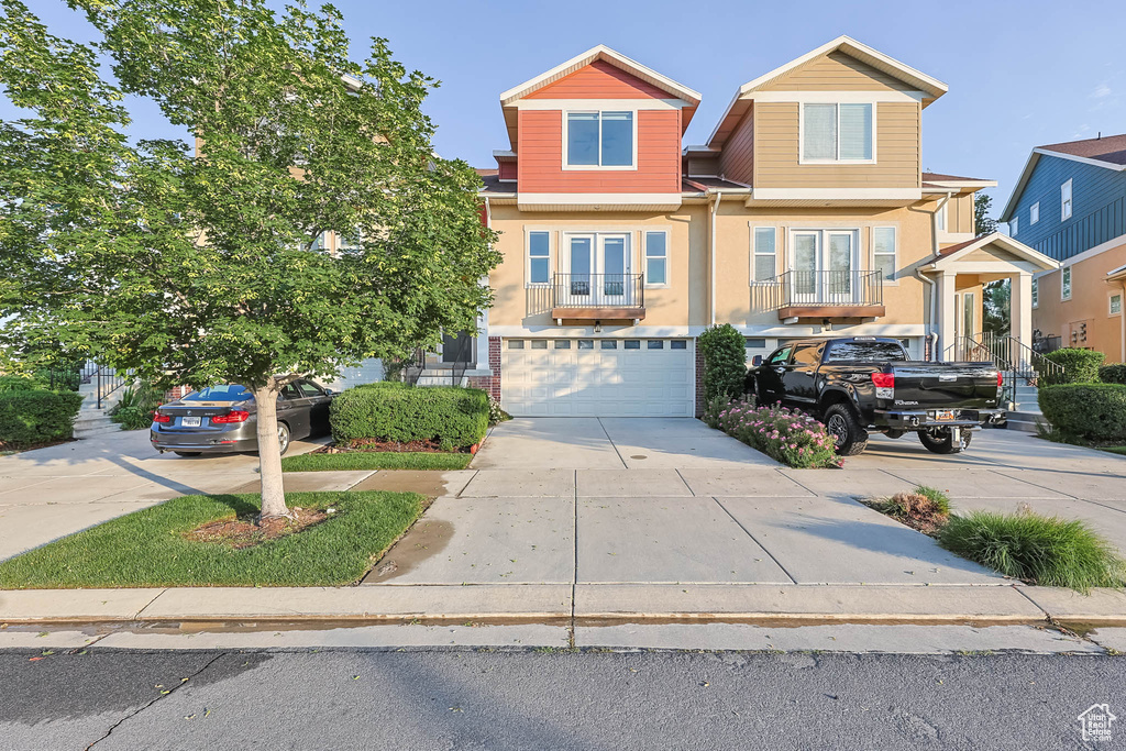 View of front facade featuring driveway, french doors, a garage, and stucco siding