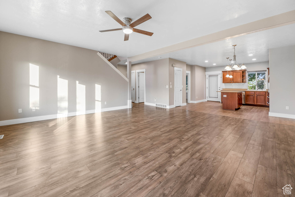 Unfurnished living room featuring a chandelier, wood finished floors, ceiling fan, and recessed lighting