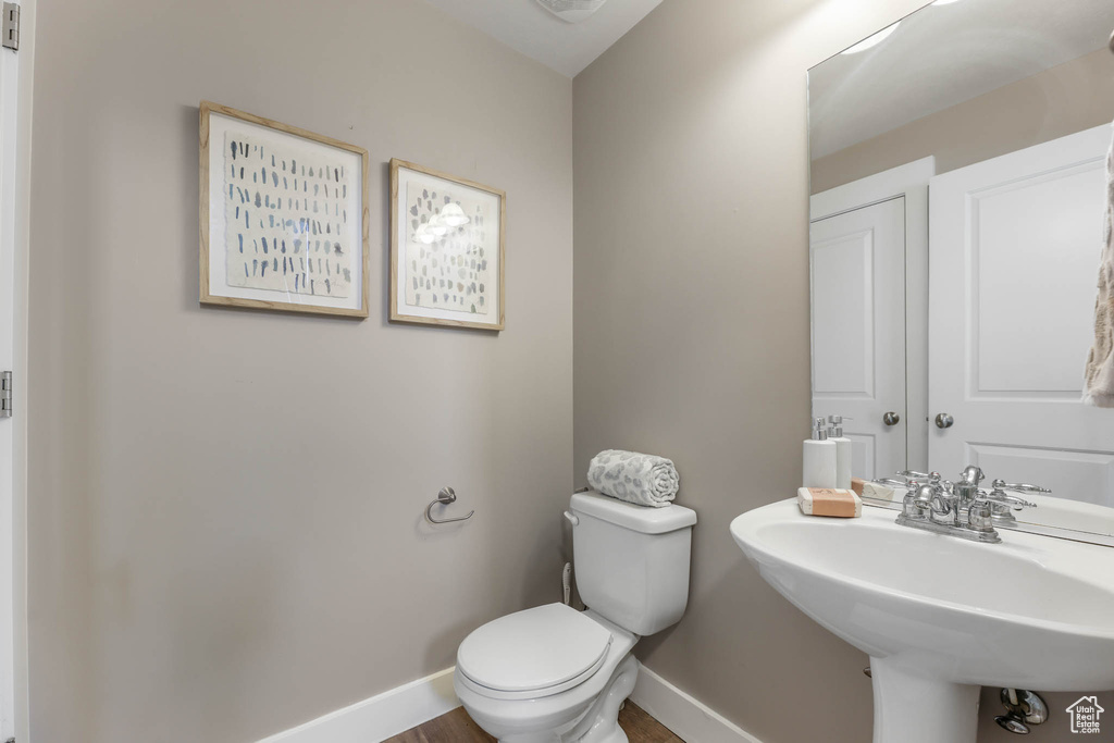 Half bathroom with toilet and wood finished floors