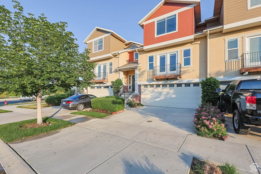 Townhome / multi-family property with concrete driveway, french doors, a garage, and stucco siding