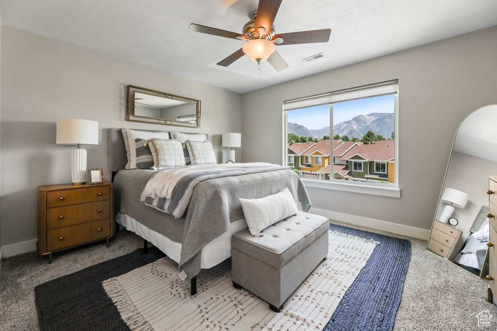 Carpeted bedroom featuring ceiling fan, arched walkways, and a mountain view