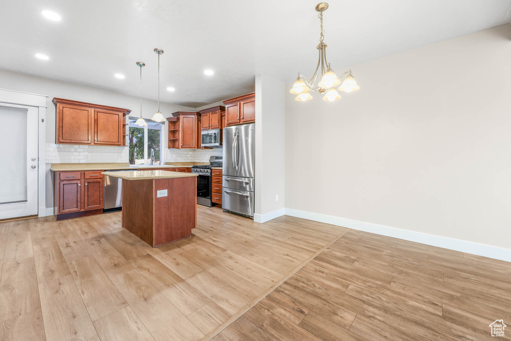 Kitchen featuring appliances with stainless steel finishes, open shelves, a kitchen island, light wood finished floors, and recessed lighting