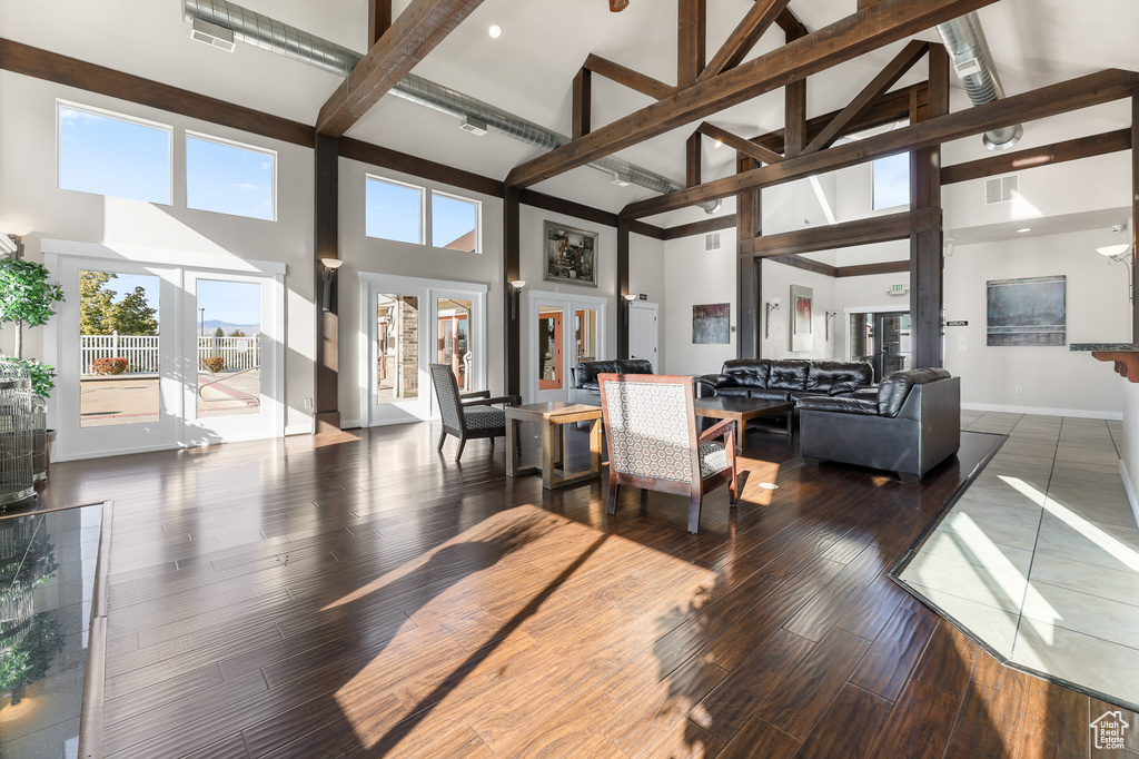 Living room featuring high vaulted ceiling, beam ceiling, wood-type flooring, and french doors