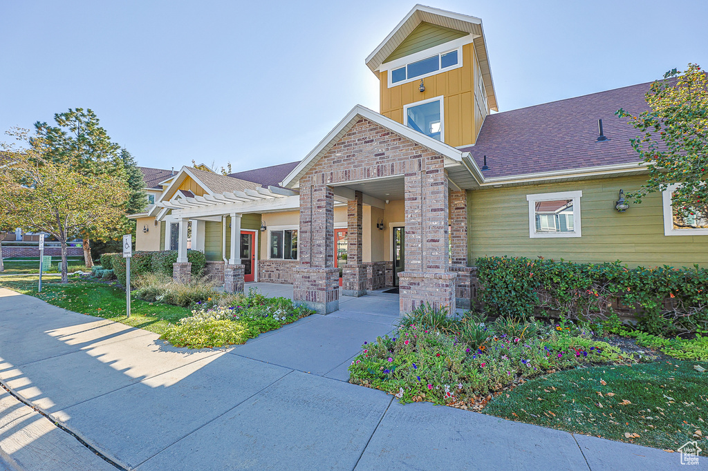 View of front of home featuring a pergola, brick siding, and a shingled roof