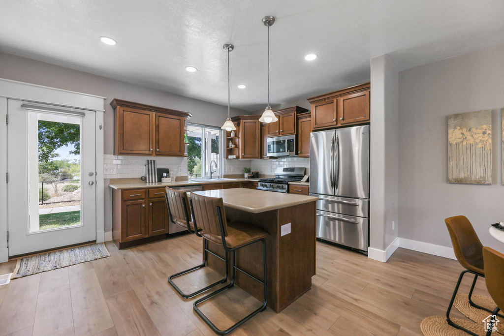 Kitchen featuring appliances with stainless steel finishes, light wood finished floors, decorative backsplash, pendant lighting, and recessed lighting