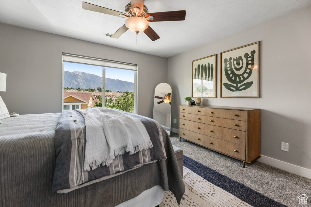 Carpeted bedroom featuring a ceiling fan, a mountain view, and access to exterior