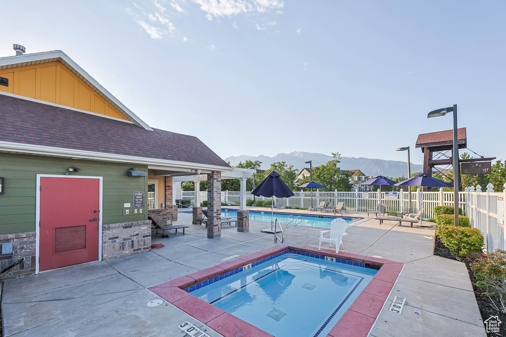 Community pool with a community hot tub, a mountain view, a patio area, and a fenced backyard