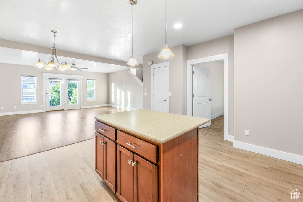 Kitchen with light wood-type flooring, brown cabinets, pendant lighting, and a center island