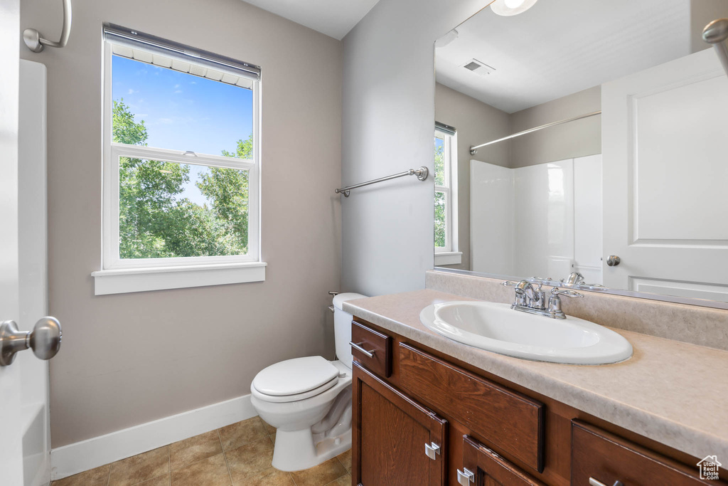 Full bath with vanity, healthy amount of natural light, a shower, and tile patterned flooring