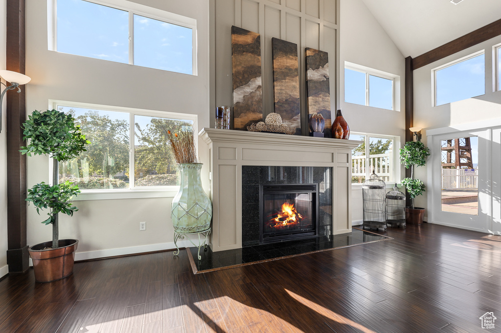 Living area with high vaulted ceiling, a tile fireplace, and dark wood-style floors