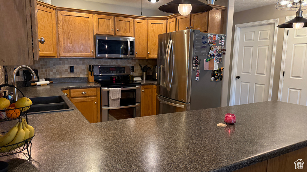 Kitchen featuring appliances with stainless steel finishes, decorative backsplash, dark countertops, and brown cabinets
