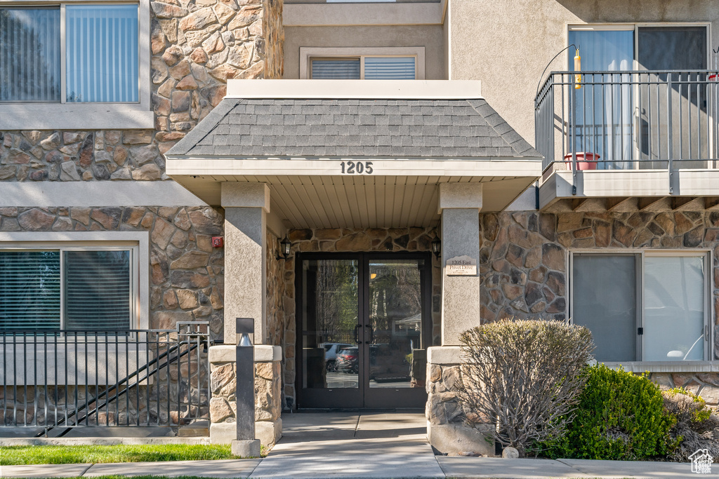 Property entrance featuring stone siding, french doors, and stucco siding