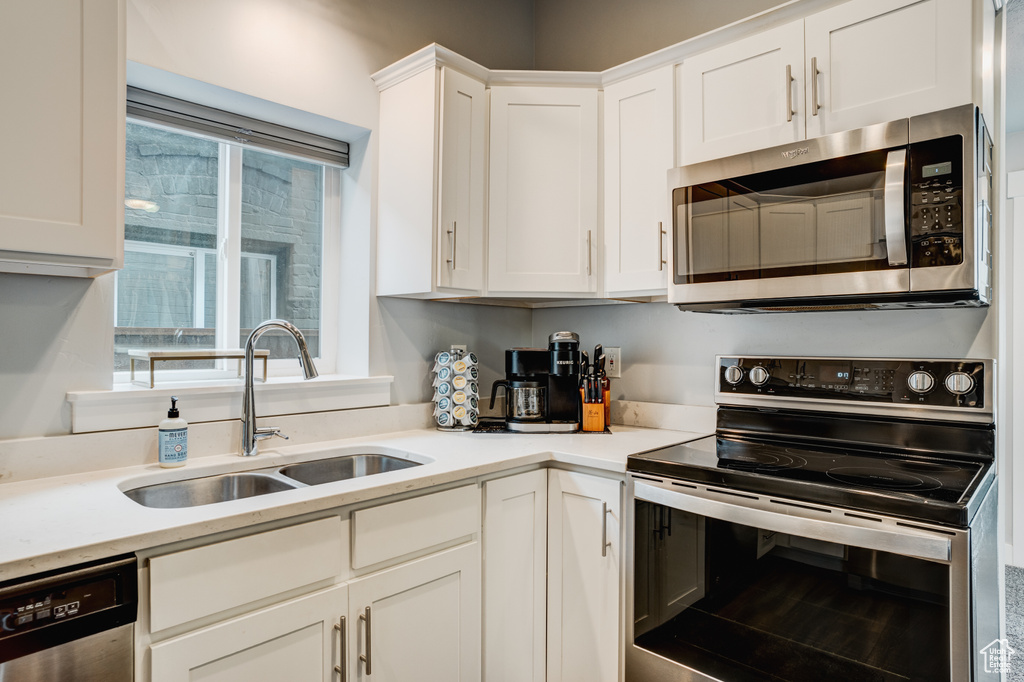 Kitchen featuring stainless steel appliances, white cabinets, and light countertops