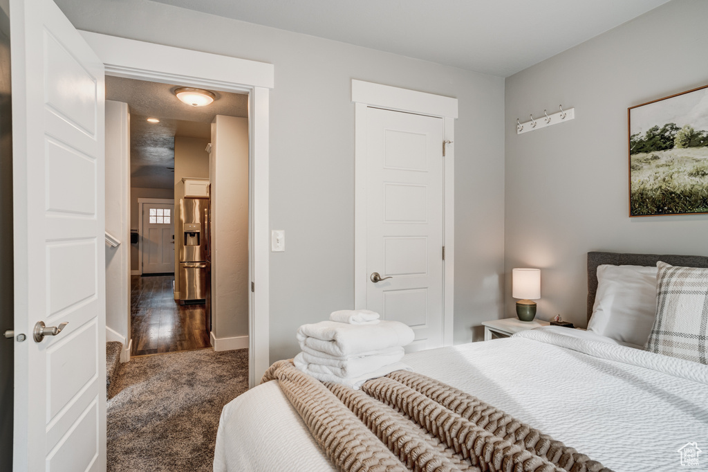 Carpeted bedroom with stainless steel fridge and baseboards