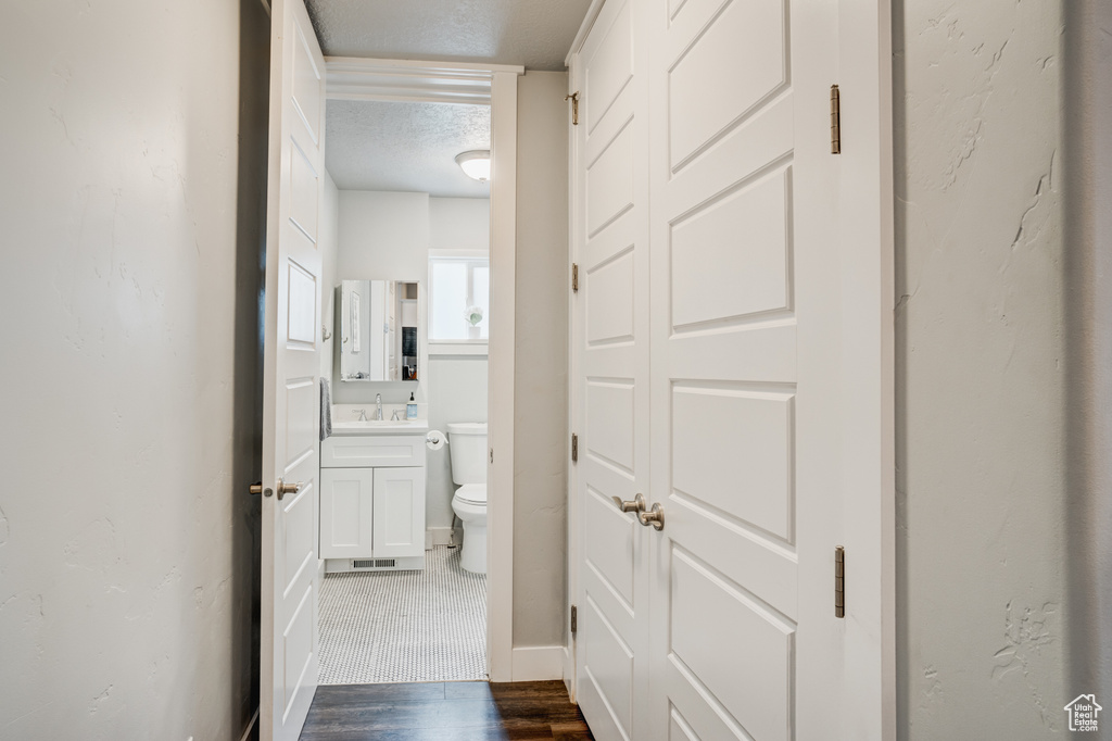 Bathroom with a textured ceiling, vanity, and wood finished floors