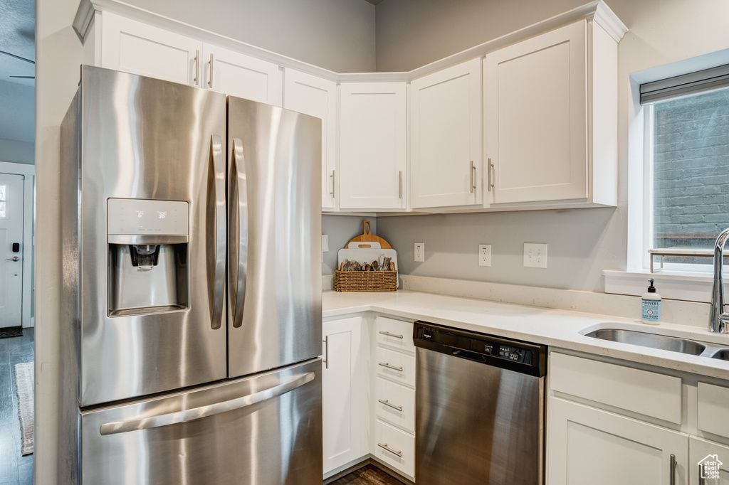 Kitchen with appliances with stainless steel finishes, white cabinets, light countertops, and dark wood-type flooring