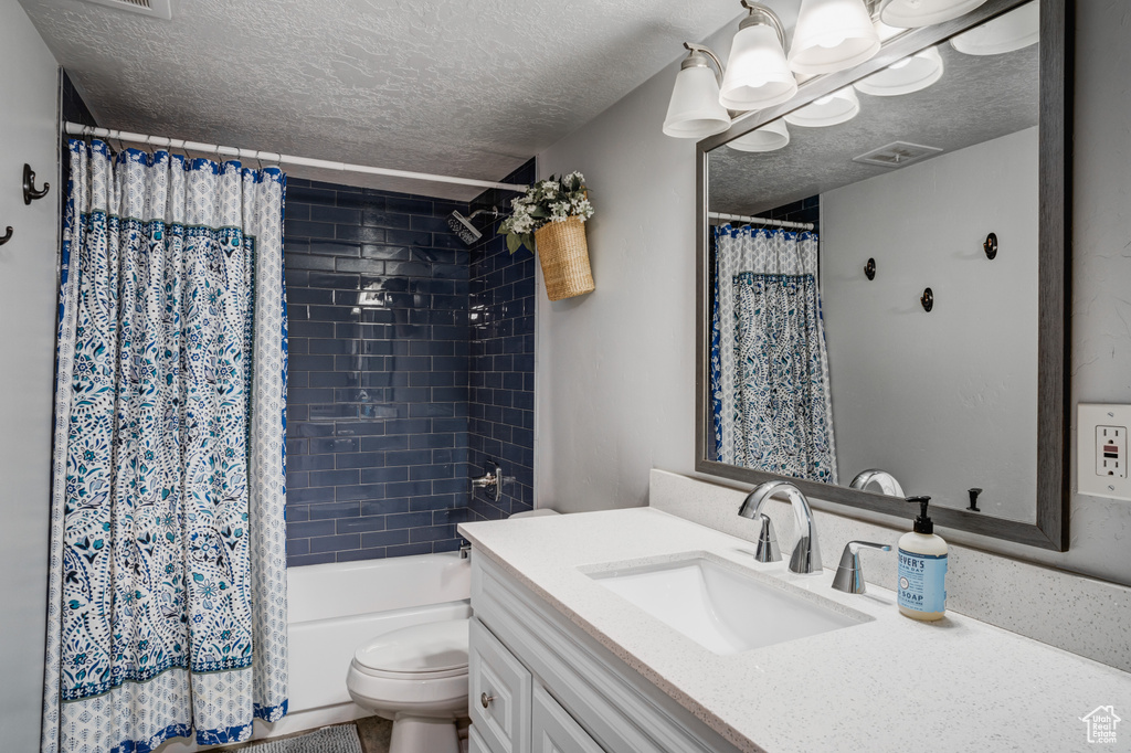 Bathroom with a textured ceiling, vanity, and shower / bath combo