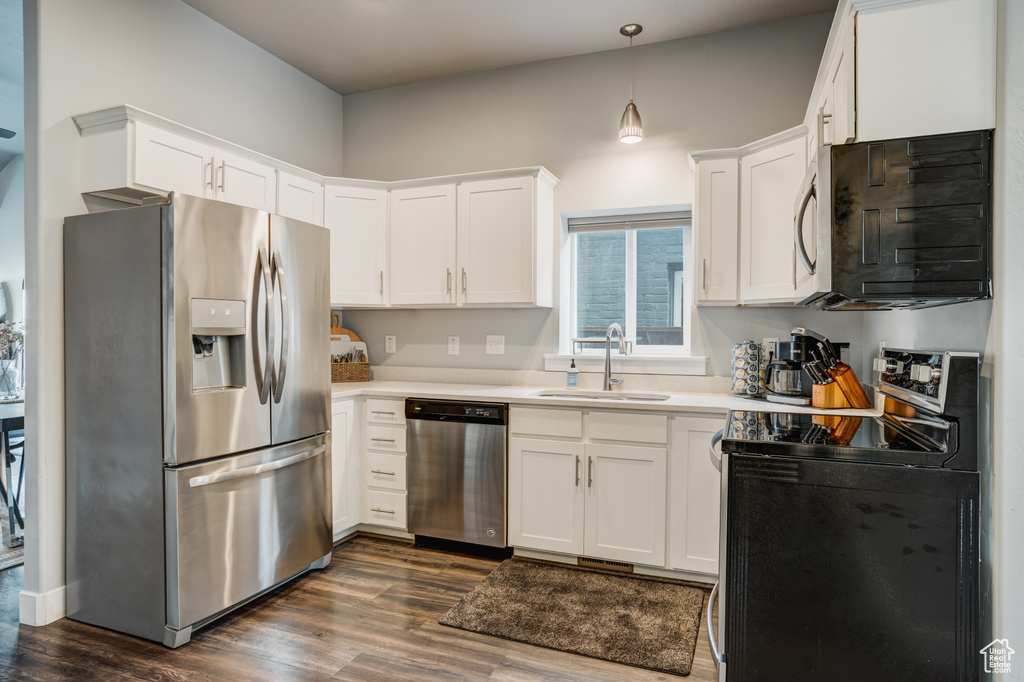 Kitchen featuring appliances with stainless steel finishes, dark wood-style flooring, and white cabinetry
