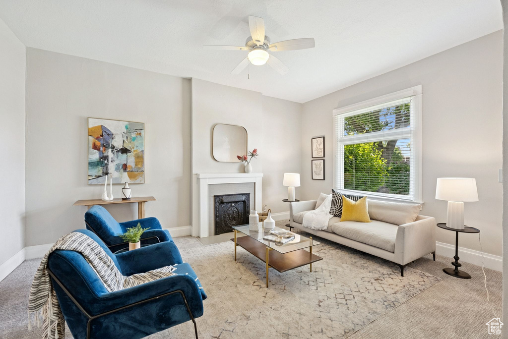 Carpeted living area featuring a fireplace and a ceiling fan