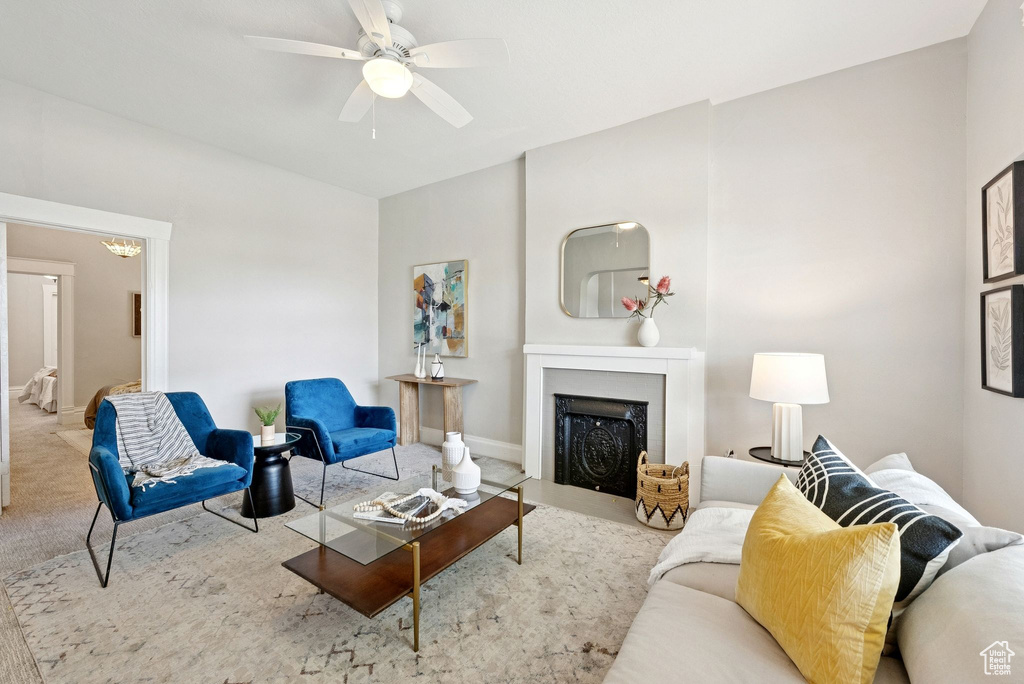 Living area featuring carpet flooring, a fireplace, a ceiling fan, and a chandelier