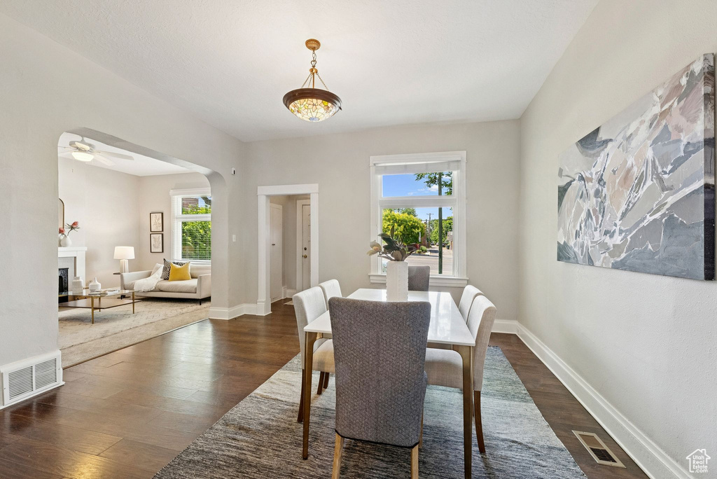 Dining room featuring dark wood finished floors, a fireplace, and arched walkways